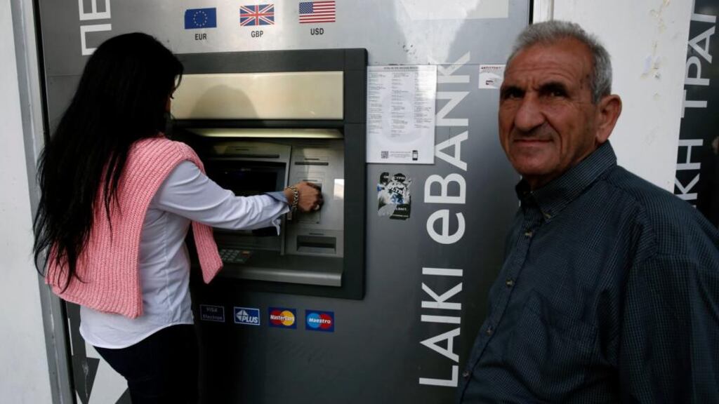 A man waits to make a transaction at a Laiki Bank ATM in Nicosia yesterday. Cyprus’s two insolvent banks are being put through resolution procedures that will see equity holders and bondholders lose out and uninsured deposits subjected to a substantial write-down. Photograph: Reuters/Yorgos Karahalis