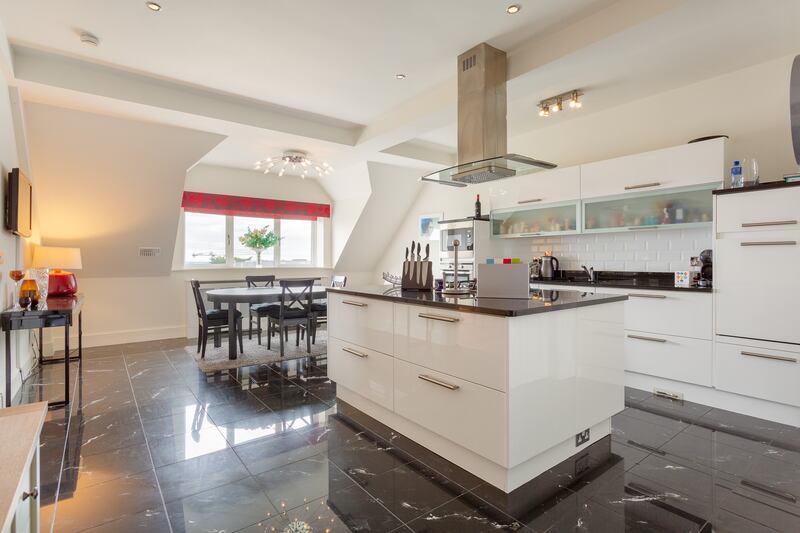 The kitchen/dining room has custom-fitted high-gloss kitchen units, polished-stone countertops and a large island