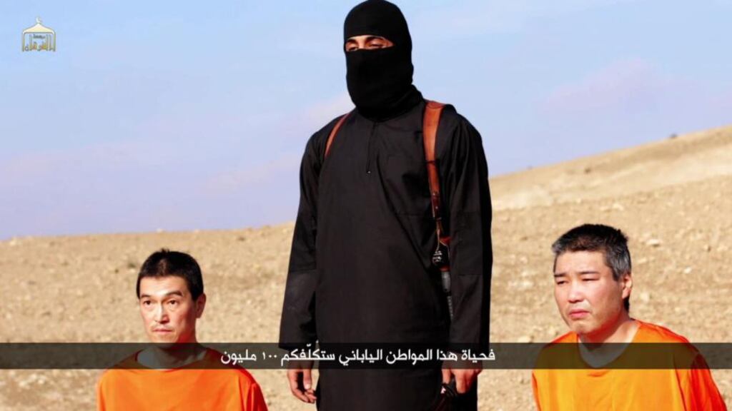 An image grab taken from a video released by the Islamic State (IS) group through Al-Furqan Media, showing Japanese hostages Kenji Goto (L) and Haruna Yukawa (R) in orange jumpsuits with a black-clad militant brandishing a knife. Photograph: AFP/Getty Images