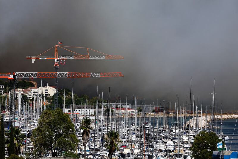 Boats moored at the Plage des Corbieres, in Marseille, France, on Tuesday, as smoke billows from a wildfire in the background. Photograph: Clement Mahoudeau/AFP