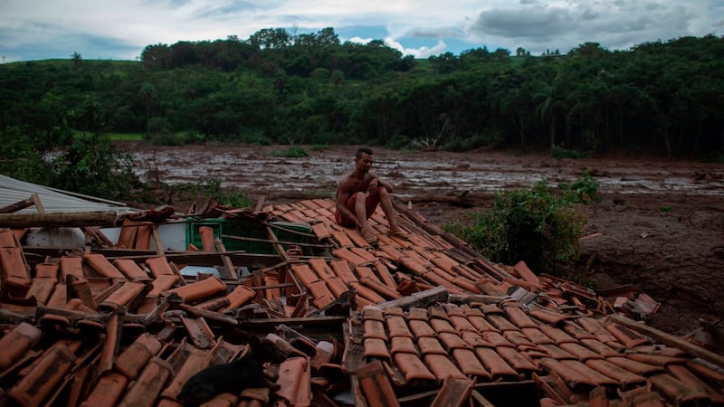 ‘Everything was shaking and I saw huge trees and people disappearing under the mud,’ said Emerson dos Santos, 30, who sits on the roof of his family home to protect what is left from looters at the mud-hit area a day after the dam collapse. Photograph: Mauro Pimentel/AFP/Getty Images