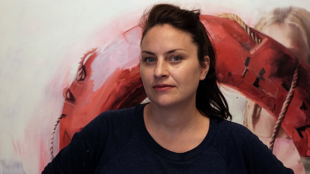 Chloe Early with her print, ‘Compass’, in the background. The work will raise money for a charity which helps refugee mothers.