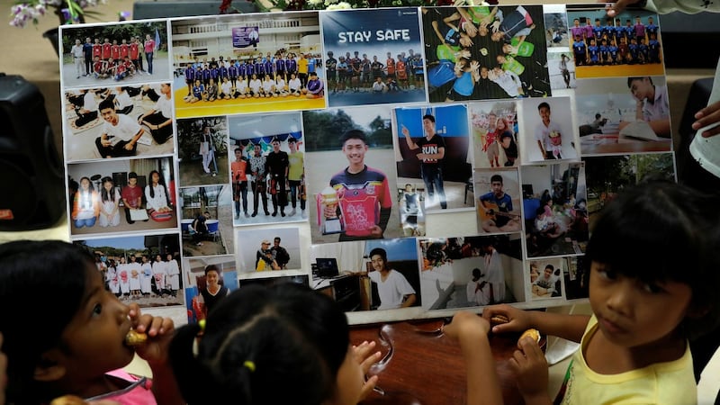 Children look at pictures of the 12 schoolboys and their soccer coach that were trapped inside a flooded cave. Photograph: Soe Zeya Tun/Reuters