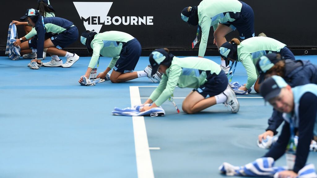 Ball kids wipe down the court after a rain delay at the Australian Open in Melbourne. Photograph: EPA