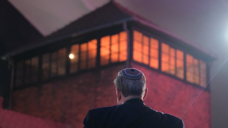 A man wearing a yarmulke stands next to the main tower at the entrance to the former Auschwitz-Birkenau concentration camp. Photograph: Sean Gallup/Getty Images