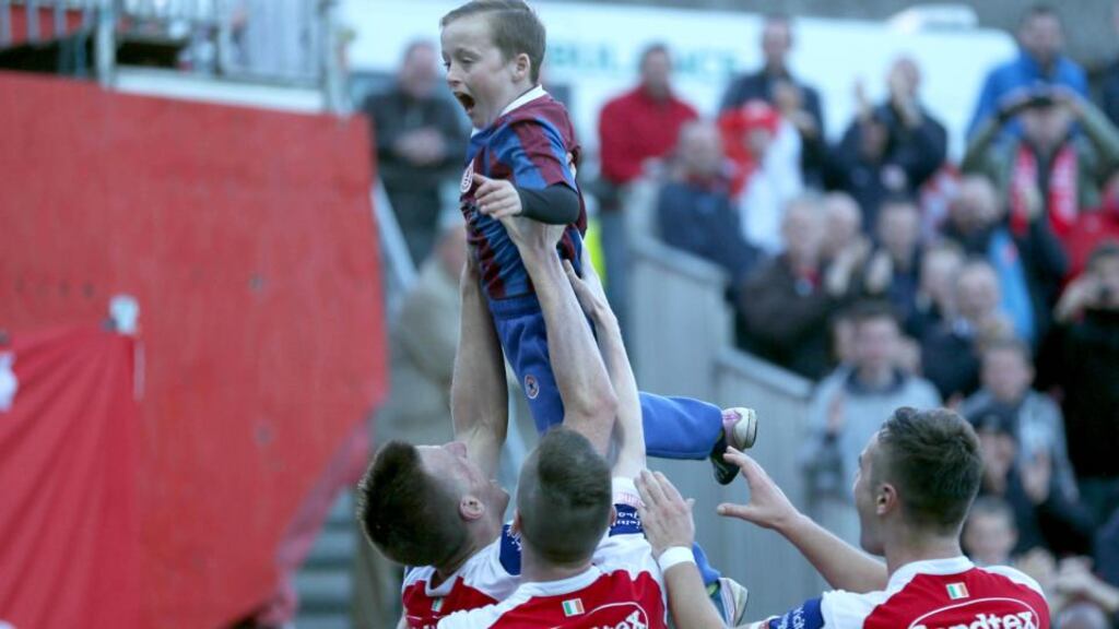 Anto Flood of St Pat’s celebrates scoring his side’s second goal of the game by lifting up a young supporter who ran on to the pitch at Richmond Park. Photograph: Donall Farmer/Inpho