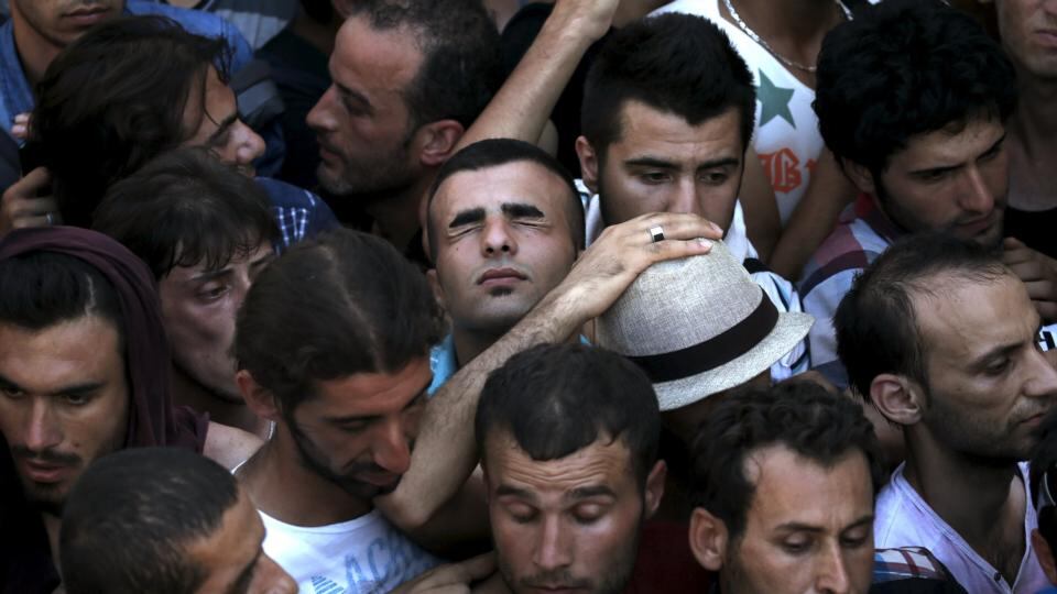 A Syrian refugee (centre) tries to catch his breath as he stands in a crowd waiting to get registered in the national stadium on Kos. Photograph: Alkis Konstantinidis/Reuters