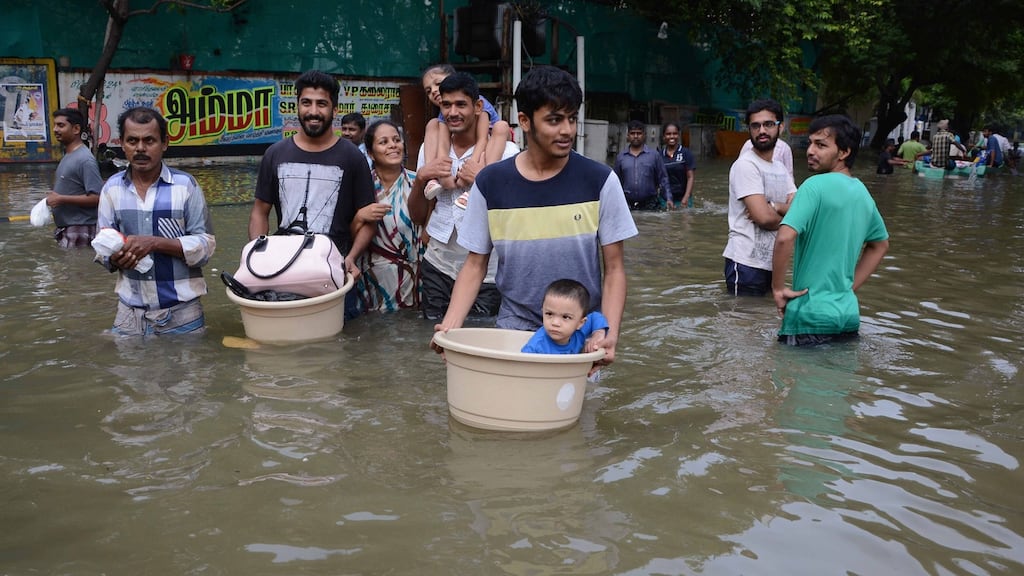 Carrying children and possessions through flood waters in Chennai, India, on Thursday. Photograph: STRSTRDEL/AFP/Getty Images