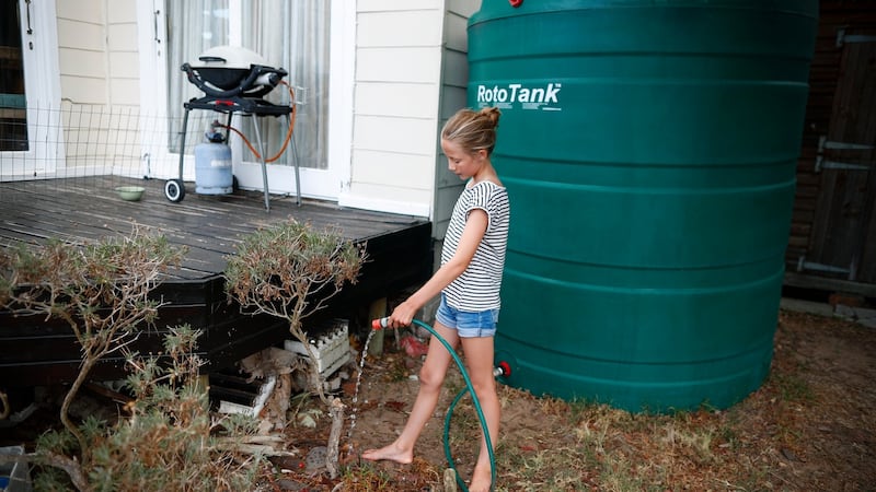 A girl waters a plant from a rainwater storage tank in Cape Town, South Africa. Watering plants using municipal water has been banned in the city. When dam levels reach 13.5 per cent, most taps will be turned off. Photograph: Nic Bothma/EPA