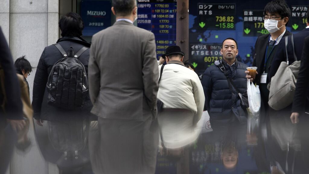Pedestrians walk past an electronic stock board outside a securities firm in Tokyo, Japan. Photographer: Tomohiro Ohsumi/Bloomberg