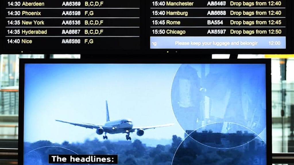A Heathrow flight information screen is shown above a television screen reporting the Ebola outbreak at Heathrow Airport in London, yesterday. Heathrow Airport has begun Ebola screening, whereby passengers will have their temperatures tested for the Ebola virus. Photograph: Andy Rain/EPA