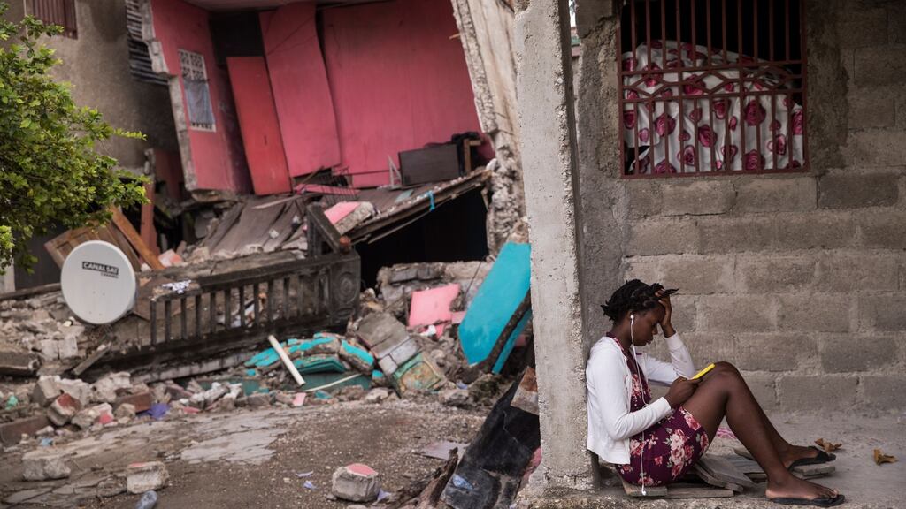 A girl checks her phone amid the wreckage in Les Cayes, Haiti, after a 7.2 magnitude earthquake hit the country. Photograph: Orlando Barria/EPA