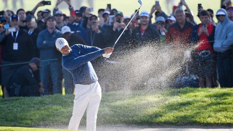 Woods hits out of the bunker on the first hole. Photo: Denis Poroy/AP Photo