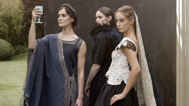 8th Panel. Haggard Queen: Abby holding a goblet wears blue chiffon dress with asymmetric hem edged with silver lace and Swarovski crystal. Blue lace crepe de chin silk shawl edged with silver lace. Vamp Queen: Maria wears blue and black spot wool crepe dress with feather boas. Lavish Queen: Thalia wears white and black antique lace fitted top over silk satin taffeta skirt with appliqued white lace motifs and a white lace antique shawl. Photograph: Barry McCall