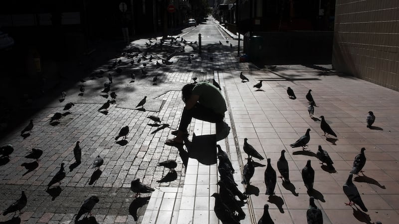 A man rests his head on his hands as pigeons fly around him in Cape Town. Photograph: Rodger Bosch/AFP via Getty