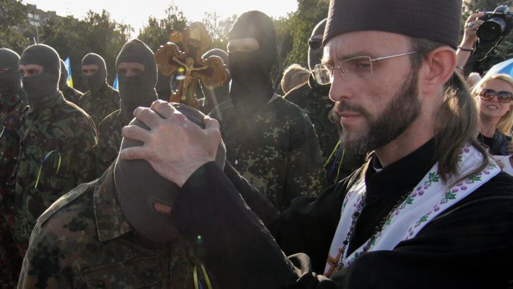 A Ukrainian priest blesses members of a people’s volunteer corps during a rally in support of single Ukraine in  Mariupol yesterday. Photograph: EPA/Photomig