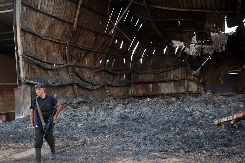 An armed resident walks amid the ashes of a heavily damaged building in kibbutz Alumim, following the October 7th attack by Hamas fighters, in southern Israel near the Gaza Strip on October 18, 2023. Photograph: Gil Cohen-Magen/Getty Images