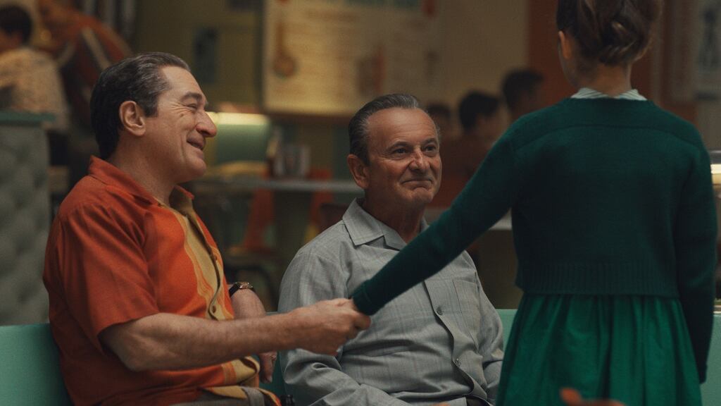 At a bowling alley, Frank Sheeran (Robert De Niro) attempts a show of warmth to his daughter Peggy (Lucy Gallina) in front of Russell Bufalino (Joe Pesci) in The Irishman. © 2019 Netlfix US, LLC.