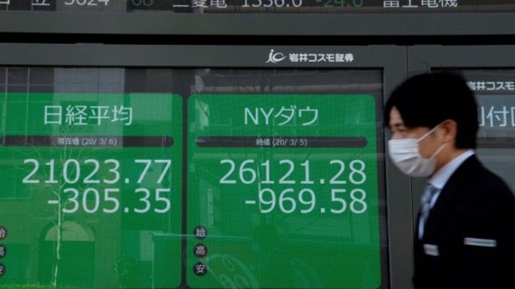 A pedestrian walks past quotation boards displaying a share price from the Tokyo Stock Exchange. Photograph: Kazuhiro Nogi/AFP