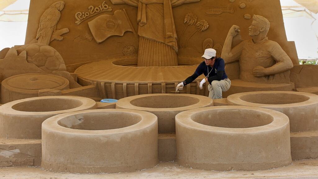 Katsuhiko Chaen, sand sculptor and Executive Director of the Sand Museum works on a Sand sculpture of the Olympic Rings below the famous Christ the Redeemer statue. Russia’s hopes of fielding a full track and field team at the Rio Olympics will be settled by the Court of Arbitration for Sport (CAS) on July 21st. Photo: Getty Images