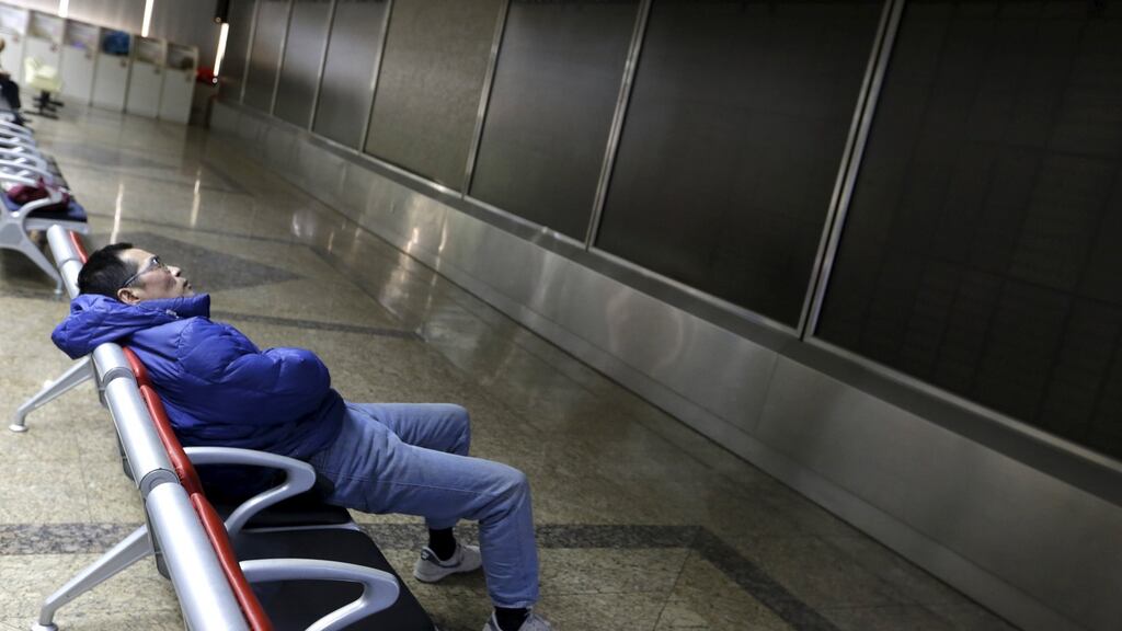 An investor rests in front of an electronic board turned off after the market suspended at a brokerage house in Beijing