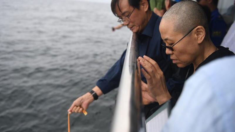 Liu Xia (right) praying as Liu Xiaobo’s ashes are lowered into the sea. Photograph: AFP
