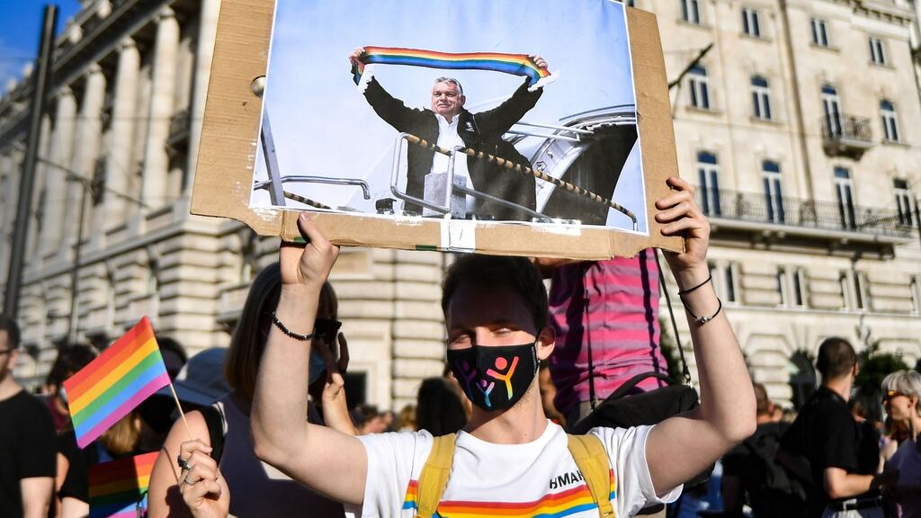 A protester’s placard shows Hungarian prime minister Viktor Orban holding a scarf in rainbow colours in front of the parliament building in Budapest. Photograph: Gergely Besenyei