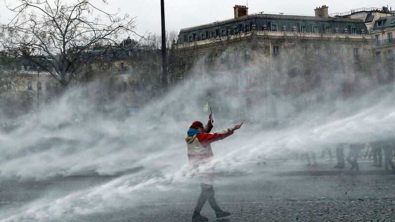 Water canon is directed at a yellow vest protester at the Arc de Triomphe in Paris. Photograph: EPA