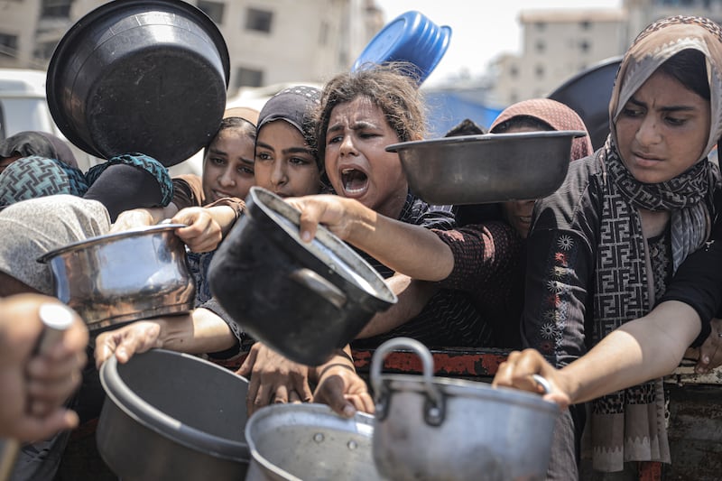 Palestinians wait with pots in their hands as a charitable organization distributes food. Photograph: Ahmed Jihad Ibrahim Al-arini/ Anadolu via Getty Images