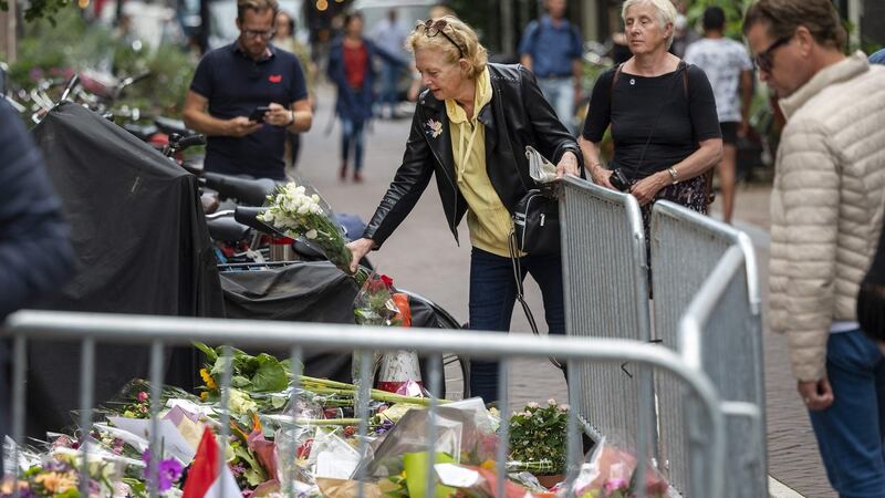A woman displays flowers past candles and messages in the Lange Leidsedwarsstraat, at the place where Peter R. de Vries was attacked on Tuesday night. Photograph: Evert Elzinga/ANP/AFP via Getty Images