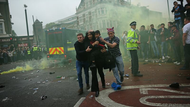 A woman and a child are helped get past after trouble flared up outisde Upton Park ahead of the Premier League game between West Ham United and Manchester United. Photograph: Dan Kitwood/Getty Images