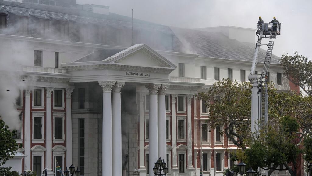 Firefighters move an elevating platform near the roof of the National Assembly building as smoke billows from a fire. Photograph: Stringer/EPA