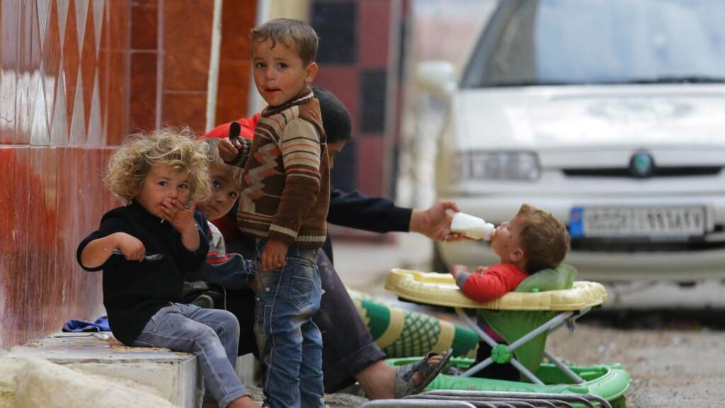 Children sit in the street as a baby drinks milk in the Duma neighbourhood of Damascus. Photograph: Bassam Khabieh/Reuters