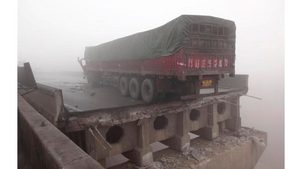 A truck sits perilously close to the edge of a bridge on the Lianhuo highway China?s Henan province that partially collapsed after a truck loaded with fireworks exploded this morning. Photograph: Reuters