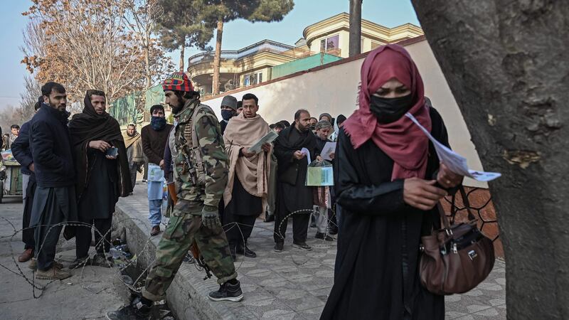 A Taliban fighter walks past people waiting to enter the passport office at a checkpoint in Kabul on Sunday, after Afghanistan’s Taliban authorities said they will resume issuing passports. Photograph: Mohd Rasfan/AFP via Getty Images