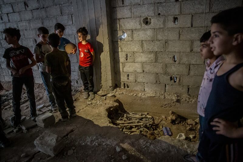 Children at a shallow pit containing dozens of bones. Tadamon was the site of a publicised massacre in April 2013 and many more killings, locals say, that went undocumented