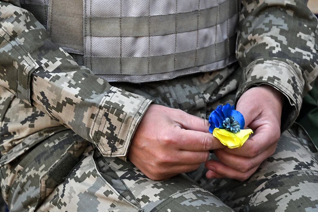 A Ukrainian woman cadet holds an artificial flower in the colour of the Ukrainian flag in Kyiv. Photograph: Sergei Supinsky/AFP via Getty Images