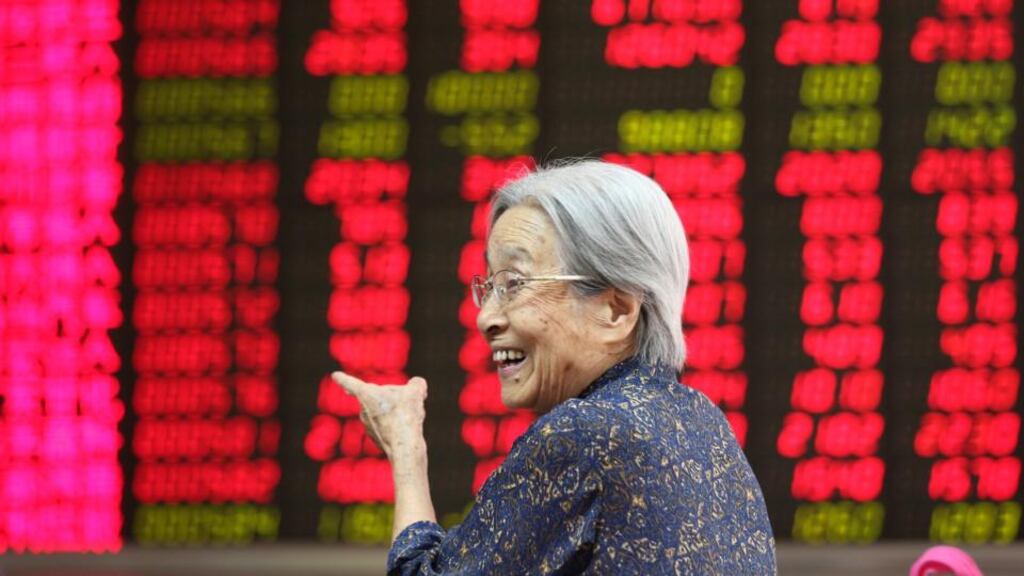 An elderly stock investor gestures in front of an electronic screen showing the stock composite index at a brokerage house in Beijing, China. Photo: EPA