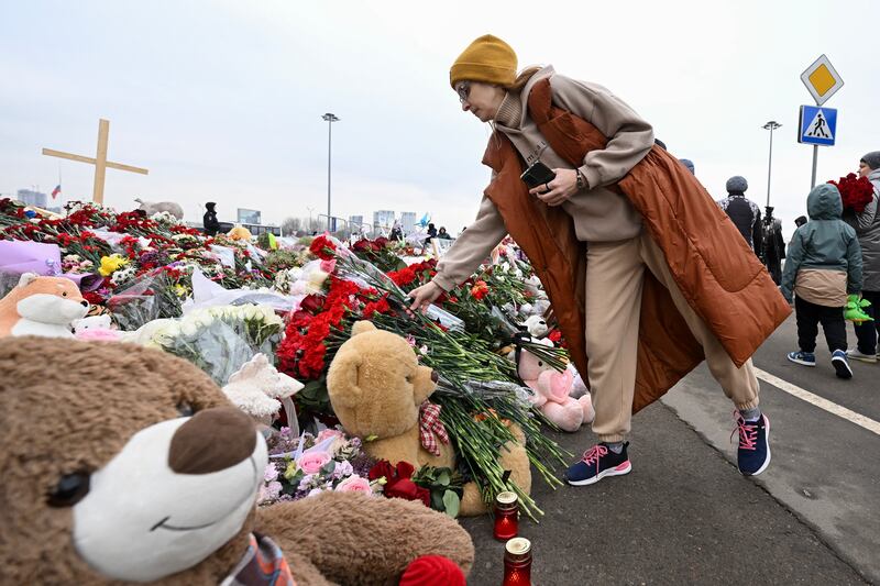 A woman lays flowers at a makeshift memorial in front of the Crocus City Hall. Photograph: Natalia Kolesnikova/AFP/Getty Images
