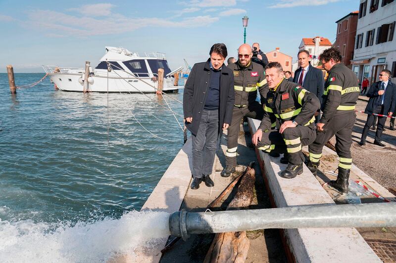 Italy’s prime minister Giuseppe Conte (centre) looks on as water is pumped out while assessing damages after the city suffered its highest tide in 50 years. Photograph: Filippo Attili/Palazzo Chigi press office/AFP via Getty