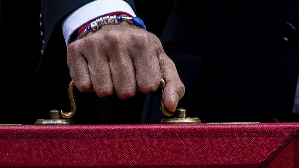 A letter block bracelet reads “dada” on the wrist of Rishi Sunak, UK chancellor of the exchequer, as he carries a dispatch box while departing from number 11 Downing Street to present his budget. Photograph: Bloomberg