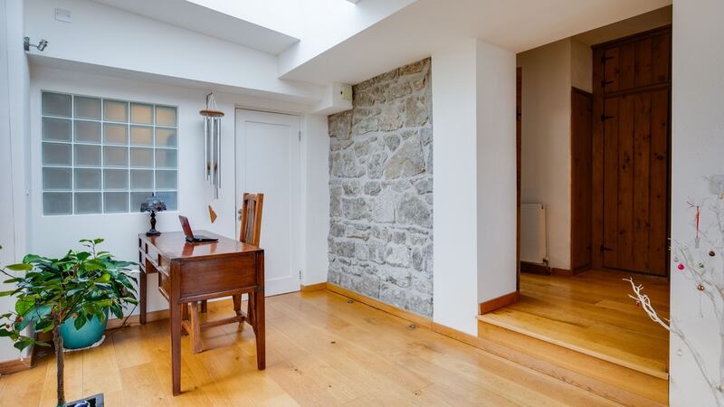 The pointed granite exterior of the back of the cottage is exposed in the hall where there is an office desk