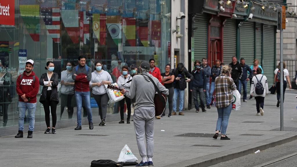 A busker entertains people queueing  outside a shop on Dublin’s Parnell Street. Photograph Nick Bradshaw