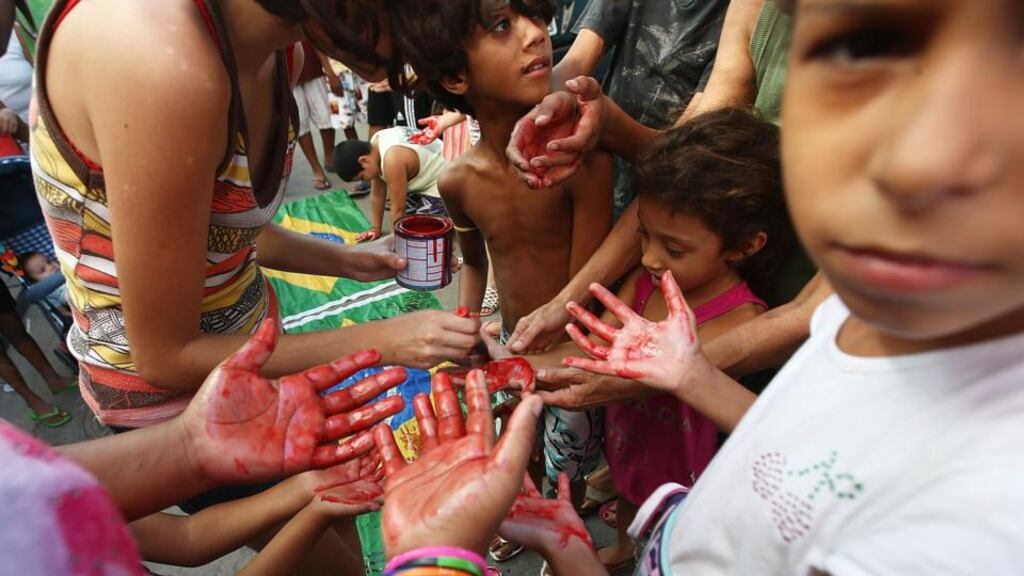 Blood on their hands: demonstrators in a Rio favela use paint to symbolise the blood of neighbours. Photograph: Mario Tama/Getty