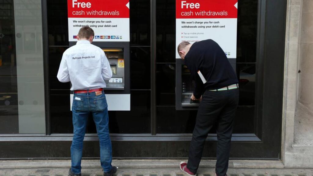 Two men use ATMs outside a HSBC bank in London. REUTERS/Suzanne Plunkett