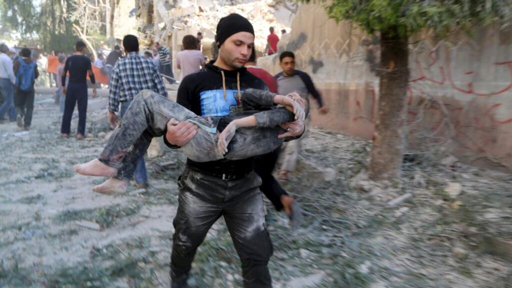A man holds an injured boy after what activists said was a barrel bomb dropped by forces loyal to Syrian president Bashar al-Assad hit a school and residential building in the Seif al-Dawla neighborhood of Aleppo. Photograph: Hosam Katan/Reuters