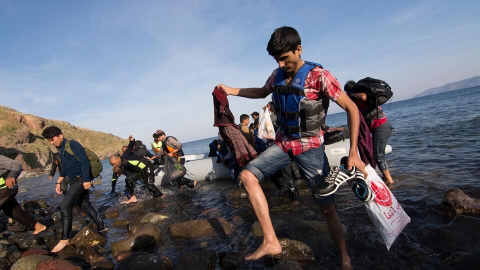 Migrants from Somalia, Pakistan and Afghanistan carry their belongs onshore after arriving by inflatable boat from Turkey on the Greek island of Lesvos on Tuesday. Most migrants landing on Lesvos are Syrian. Photograph: Nikolas Georgiou