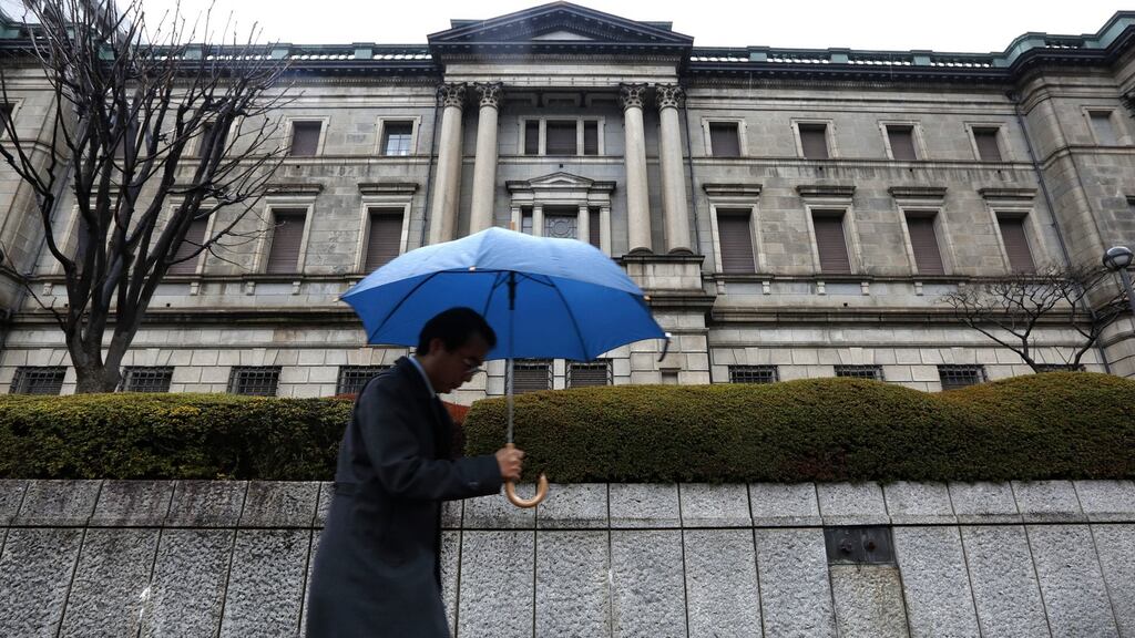 A pedestrian holding an umbrella walks past the Bank of Japan (BOJ) headquarters in Tokyo, today. Photo: Bloomberg