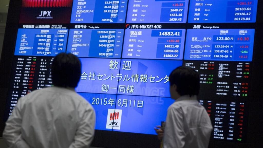 Men look at a display showing market indices at the Tokyo Stock Exchange (TSE) in Tokyo . Photograph: Thomas Peter/REUTERS