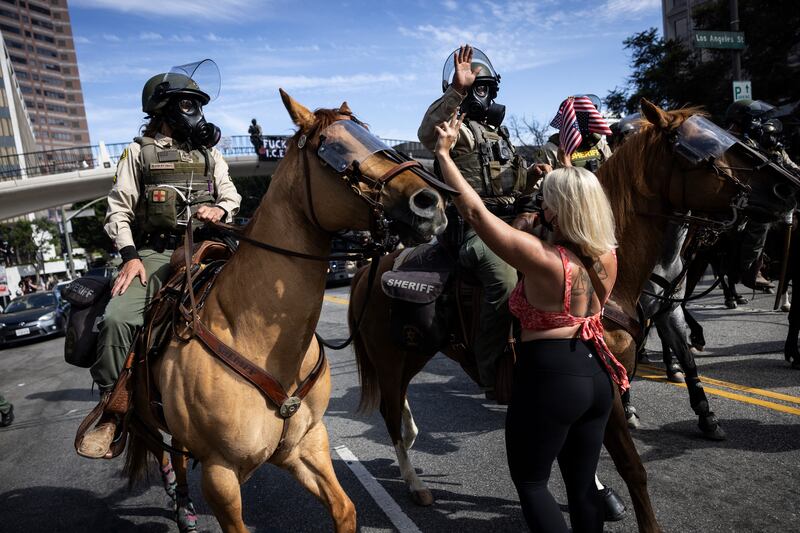 A woman gestures at mounted police moving in to disperse protesters in Los Angeles. Photograph: Etienne Laurent/AFP via Getty Images